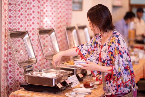 a woman is preparing food in a buffet at Hotel Arya Niwas in Jaipur