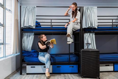 a man and a woman sitting on top of bunk beds at Summer House Sydney City in Sydney