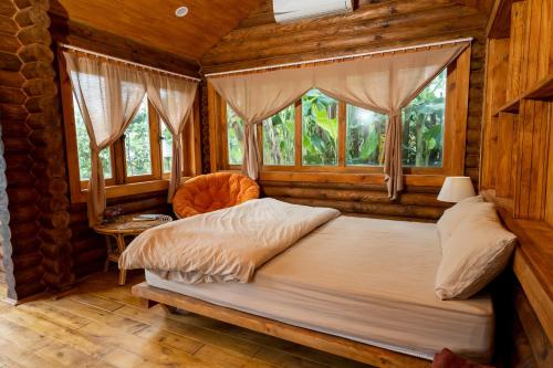 a bedroom with a bed in a room with windows at Mộc An Nhiên Farmstay in Pleiku