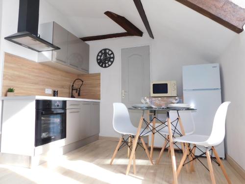 une cuisine avec une table, des chaises et une horloge dans l'établissement Appartement tout équipé à 100m du centre Thermal, à Lamalou-les-Bains