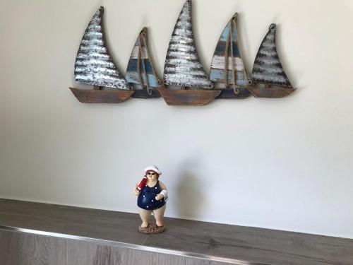 a doll sitting on a shelf with a row of sailboats at STANMA Heimat am Meer 100 m zum Meer mit Strandkorb in Büsumer Deichhausen