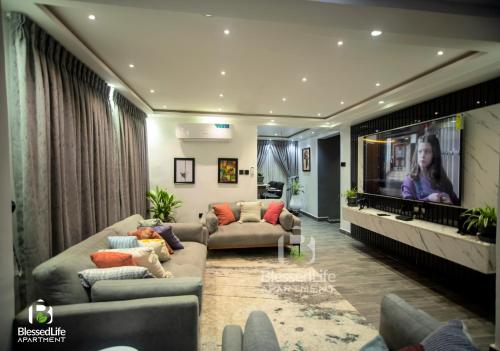 a living room with couches and a flat screen tv at Blessedlife Apartment in Kumasi