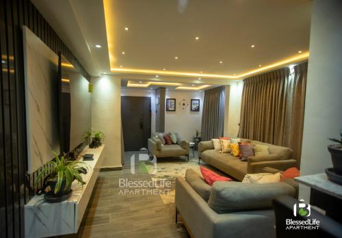 a living room with couches and chairs and a television at Blessedlife Apartment in Kumasi