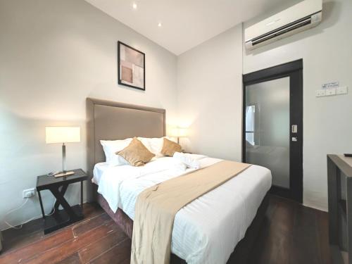 a bedroom with a large bed and a night stand with a lamp at Cozy Home 3BR 8pax The Prive Malacca Jonker Street in Melaka