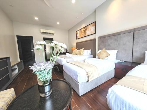a hotel room with two beds and a table with flowers at Cozy Home 3BR 8pax The Prive Malacca Jonker Street in Melaka