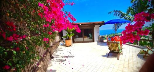 a patio with pink flowers and a blue umbrella at Villa Panorama Isola di Ischia in Ischia