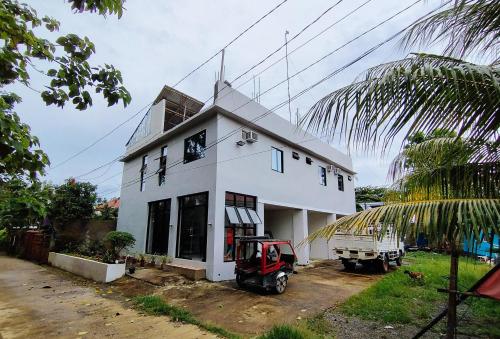 a white house with a tractor parked in front of it at RedDoorz at Elton Guesthouse in Numancia