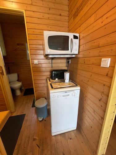une petite cuisine avec un micro-ondes et un réfrigérateur dans l'établissement Chalet les pieds dans l'eau, à Lacapelle-Viescamp