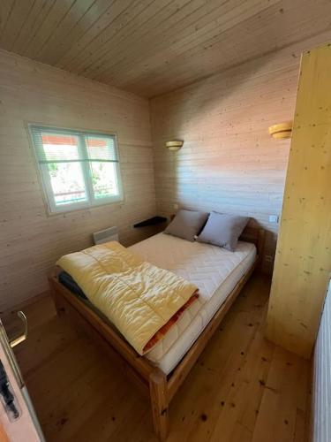 une chambre avec un lit dans une pièce en bois dans l'établissement Chalet les pieds dans l'eau, à Lacapelle-Viescamp