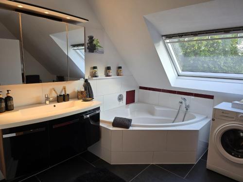 a bathroom with a tub and a sink and a washing machine at Ferienwohnung Morgensonne Mölln in Mölln