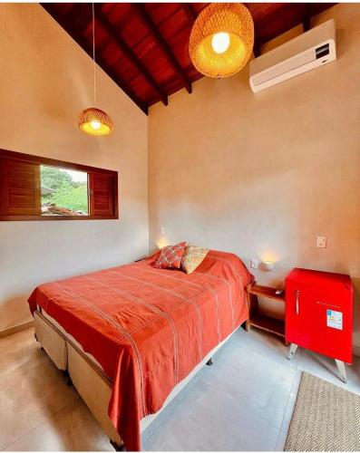 a bedroom with a large bed with a red blanket at Vila Maluhia - Chalés in Sao Jorge