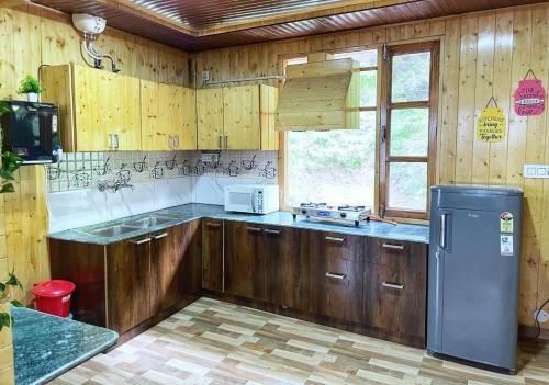 a kitchen with wooden cabinets and a refrigerator at Tranquil Trails in Barog