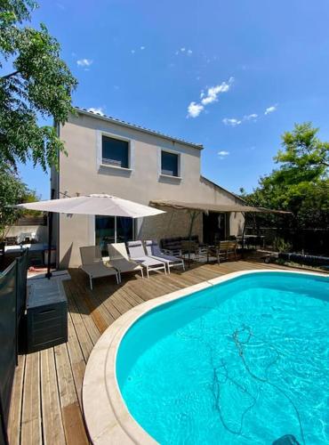 - une piscine avec des chaises et un parasol à côté d'une maison dans l'établissement VILLA au CALME avec PISCINE PRIVÉE du SAMEDI au SAMEDI, à Gigean