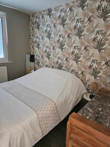 une chambre avec un lit avec un papier peint fleuri dans l'établissement La Sauvagerie, à Le Portel