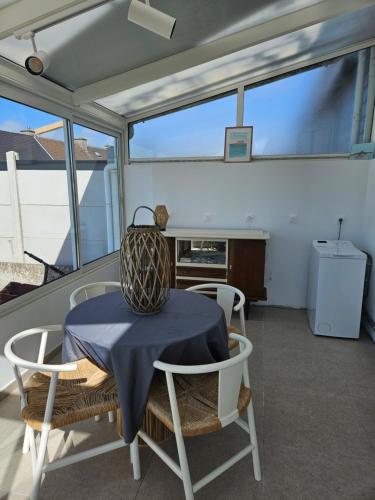 a table and chairs in a room with windows at La Sauvagerie in Le Portel