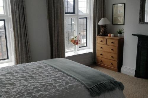 a bedroom with a bed and a dresser with windows at Estuary View Bank House Stunning apartment in Millom