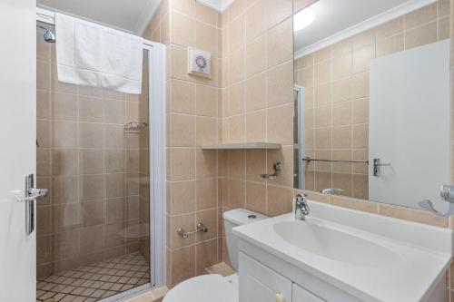 a bathroom with a shower and a toilet and a sink at The Waves 302 in Bloubergstrand