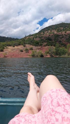 a woman laying on a boat on a body of water at Escale au Salagou in Le Bosc