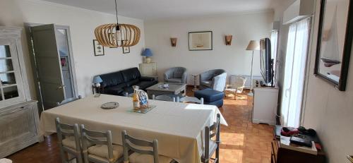 un salon avec une table avec des chaises et un salon dans l'établissement Maison proche plage et commerces, à Pénestin