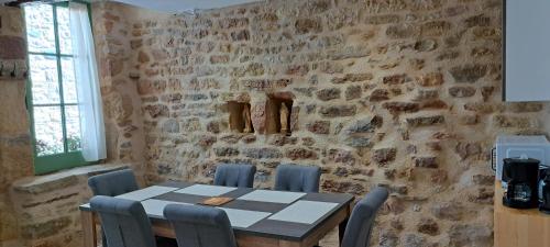 une table et des chaises dans une pièce avec un mur en pierre dans l'établissement Charmante maison de village, à Saint-Côme-dʼOlt