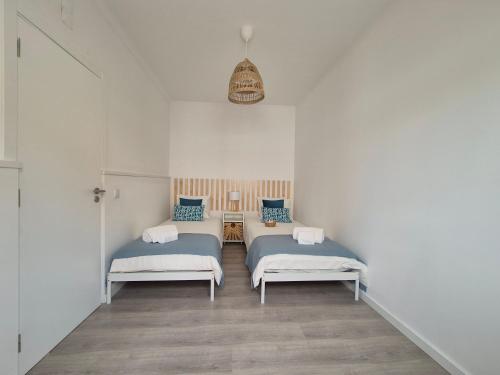 two beds in a room with white walls at Pêra Holiday House in Pêra