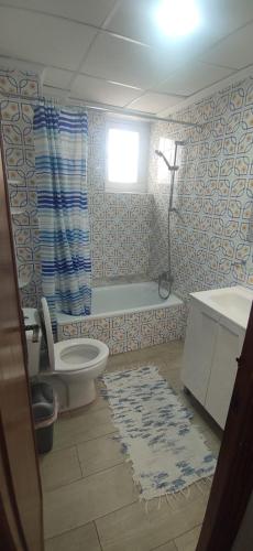 a bathroom with a toilet and a tub and a window at Appartement Spacieux fonctionnel Parking assuré!! in Novelda
