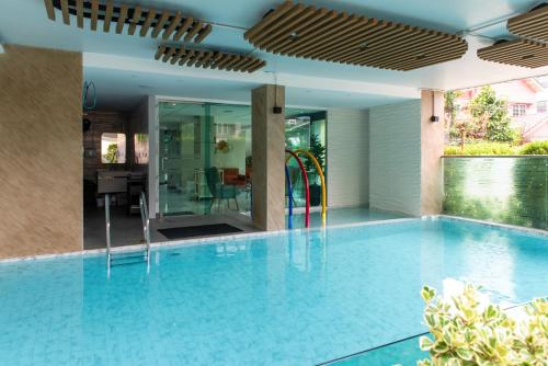 an indoor swimming pool with a blue tile floor and a house at Resort Bangphlat in Bang O