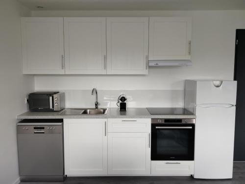 une cuisine avec des armoires blanches, un évier et un micro-ondes dans l'établissement Appartement Studio tout équipé refait à neuf, à Rambouillet