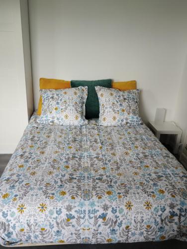 - un lit avec une couette et des oreillers bleus et blancs dans l'établissement Appartement Studio tout équipé refait à neuf, à Rambouillet