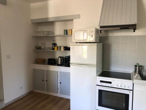 une cuisine avec des appareils électroménagers blancs et des armoires blanches dans l'établissement T2 avec terrasse calme et ensoleillée, à Saint-Claude