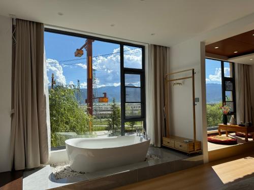 un ampio bagno con una grande vasca di fronte a una finestra di 茨姆极光民宿 a Shangri-La