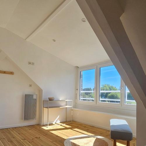 Cette chambre mansardée dispose d'une grande fenêtre et d'une chaise. dans l'établissement Les bois flottés, à La Richardais