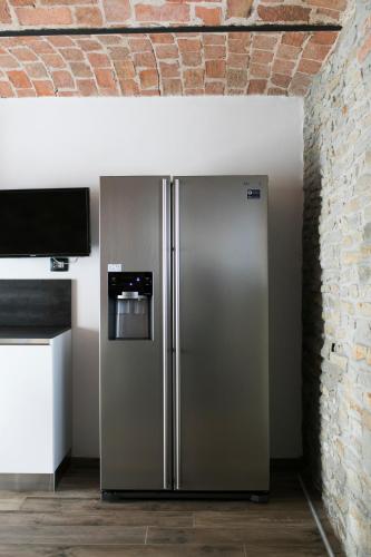 a stainless steel refrigerator in a kitchen next to a brick wall at Country House Villa Barbero - Entire House in Mango