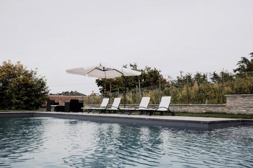 a group of chairs and an umbrella next to a pool at Country House Villa Barbero - Entire House in Mango