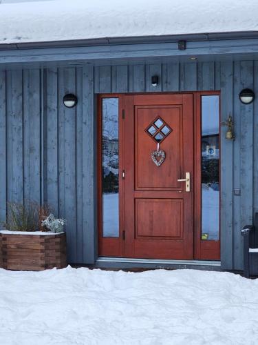 a red door on a house with snow on the ground at Jaunstūrīši in Ādaži