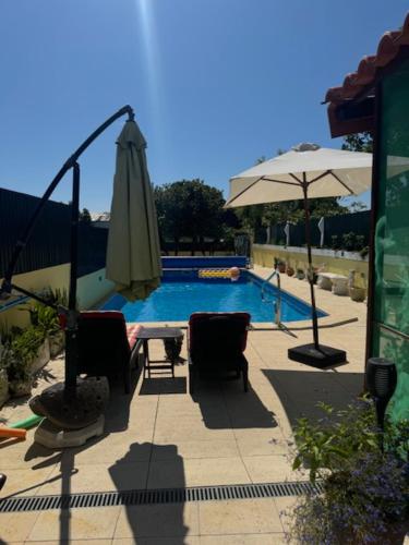 a pool with a umbrella and chairs and a table and an umbrella at 200M - Train Station Barrinha Beach House & Pool in Esmoriz