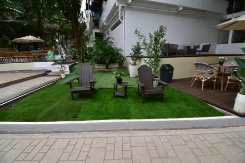 two chairs and a table on a patch of grass at Don Arc White Beach Resort in Initao