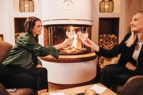 two women holding glasses of wine in a bar at Hotel Schneider Dependance in Obertauern