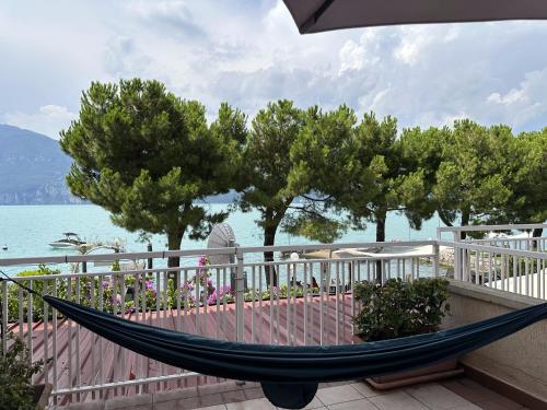 a hammock sitting on a balcony next to the water at Apartment Du Lac by GardaDoma in Brenzone sul Garda