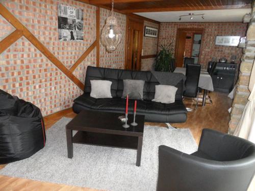 a living room with a black couch and a table at The Cottage and The Loft in Amblève