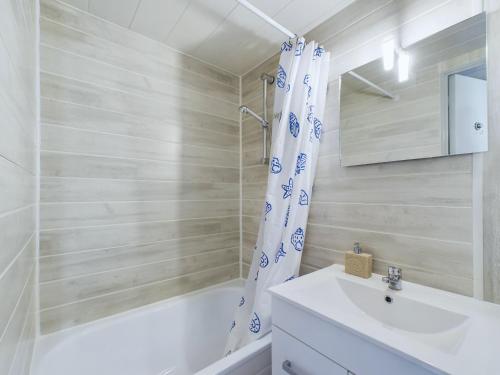 a bathroom with a sink and a shower curtain at À 150m de la plage, appartement mezzanine pour 4 in Les Bussolleries