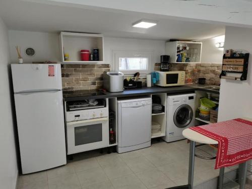 Il comprend une cuisine équipée d'appareils électroménagers blancs et d'un réfrigérateur blanc. dans l'établissement Maison 47m2 à 800 m de la plage, à Saint-Raphaël