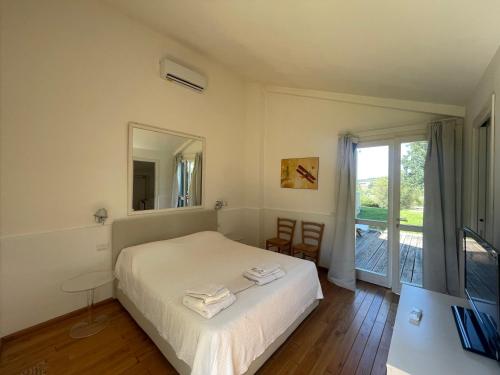 a bedroom with a bed with a mirror and a window at Villaimmersanellecollinetoscane in Pescia Romana