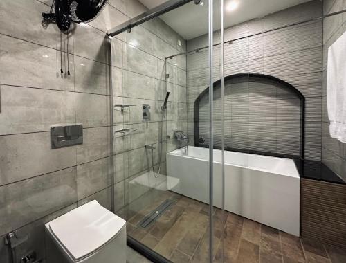 a bathroom with a tub and a toilet and a shower at Mayilveedu Guest House in Tuticorin