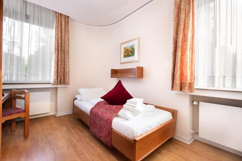a hotel room with two beds and a chair at Zur Windmühle Restaurant - Hotel in Beckum