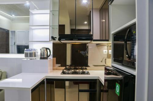 a kitchen with a stove and a microwave at Comfort 2BR Apartment at 30th Floor Transpark Cibubur By Travelio in Depok
