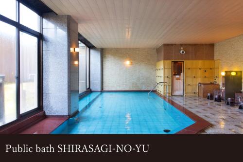 a large swimming pool in a building with a pool at Yamanaka Onsen Kissho Yamanaka in Kaga
