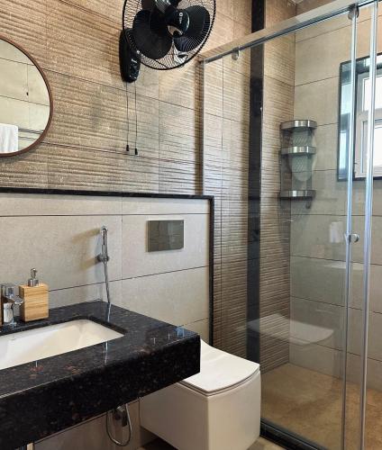a bathroom with a toilet and a glass shower at Mayilveedu Guest House in Tuticorin