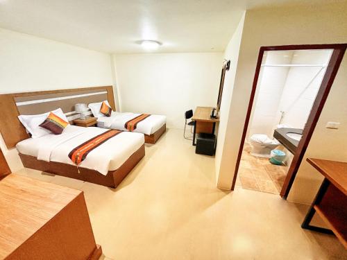 a hotel room with two beds and a bathroom at patong v hotel in Patong Beach