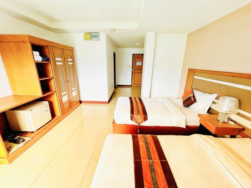 a hotel room with two beds and a desk at patong v hotel in Patong Beach